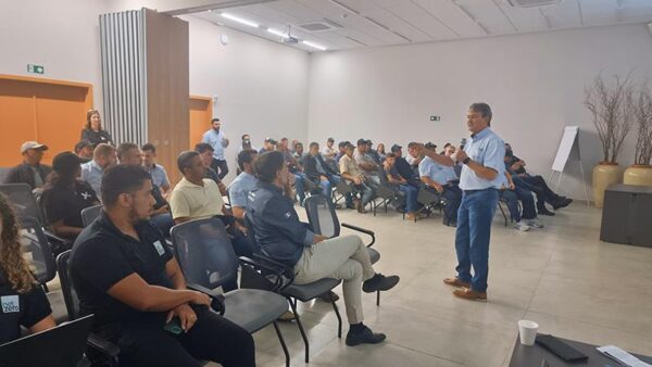 Sala de premiação cheia de participantes e representante da cooperativa discursando